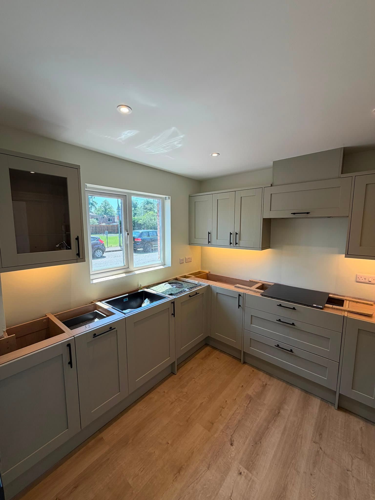 Modern grey kitchen with under-cabinet lighting and induction hob - kitchen fitter West Sussex